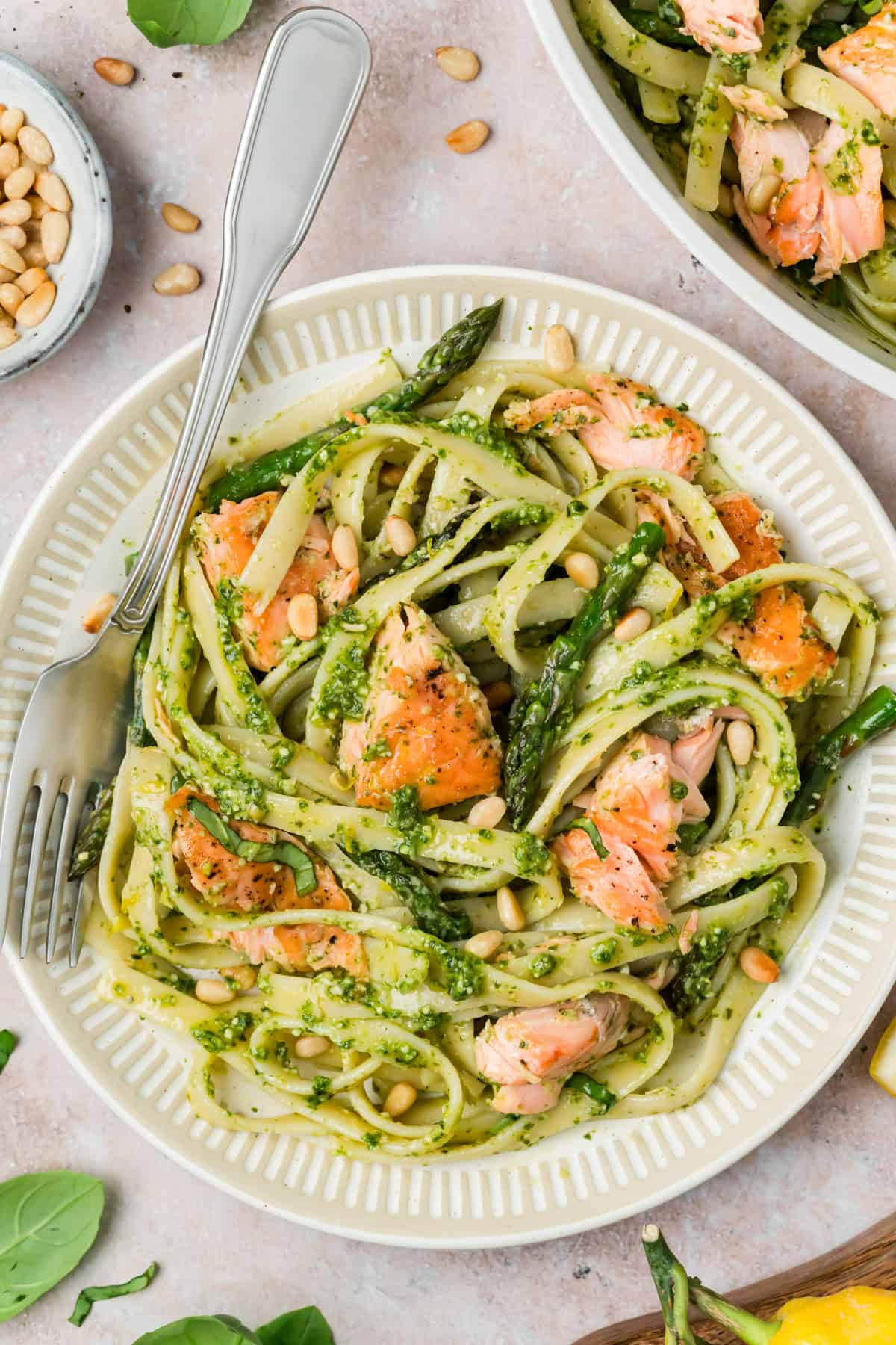 Close up of flaky pan seared salmon over pesto fettuccine with asparagus and Parmesan