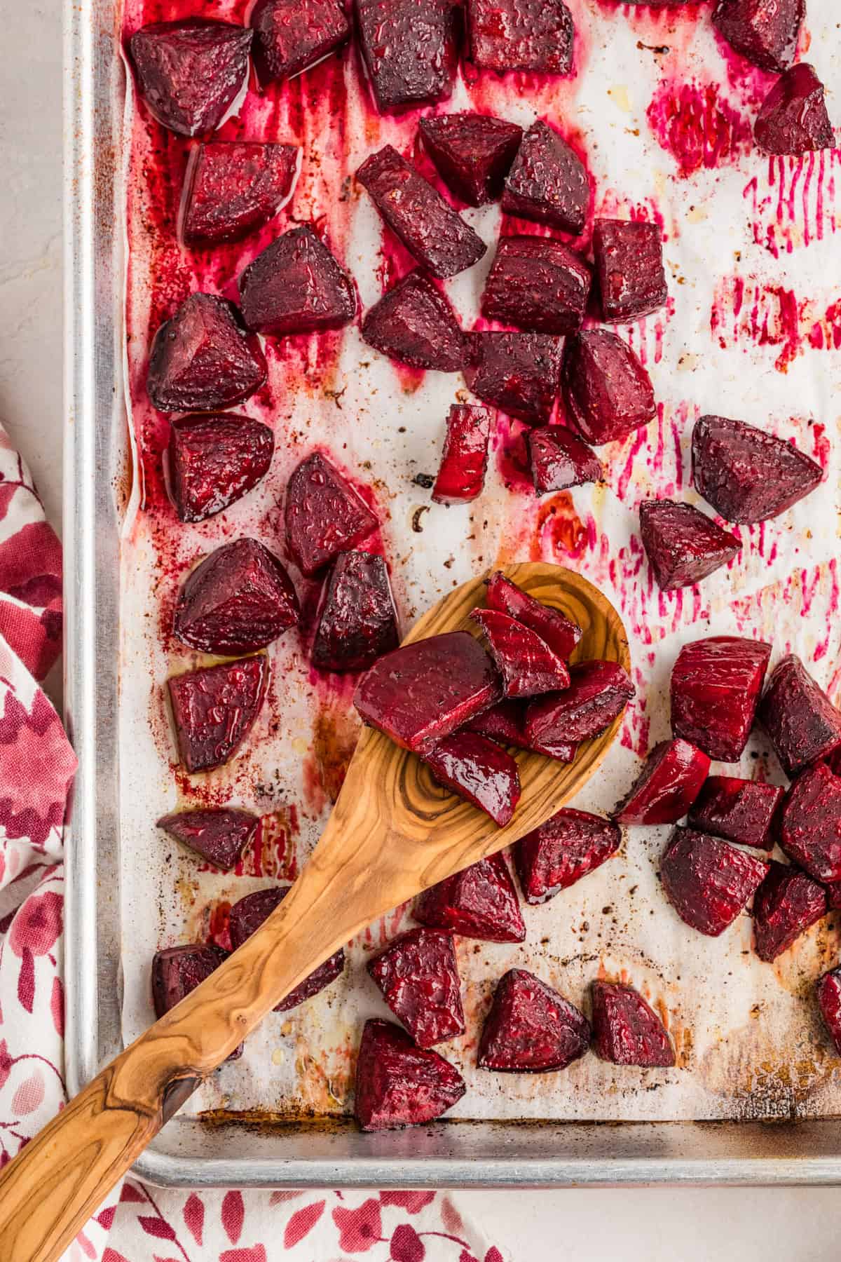 Roasted beets on a baking sheet with a wooden spoon