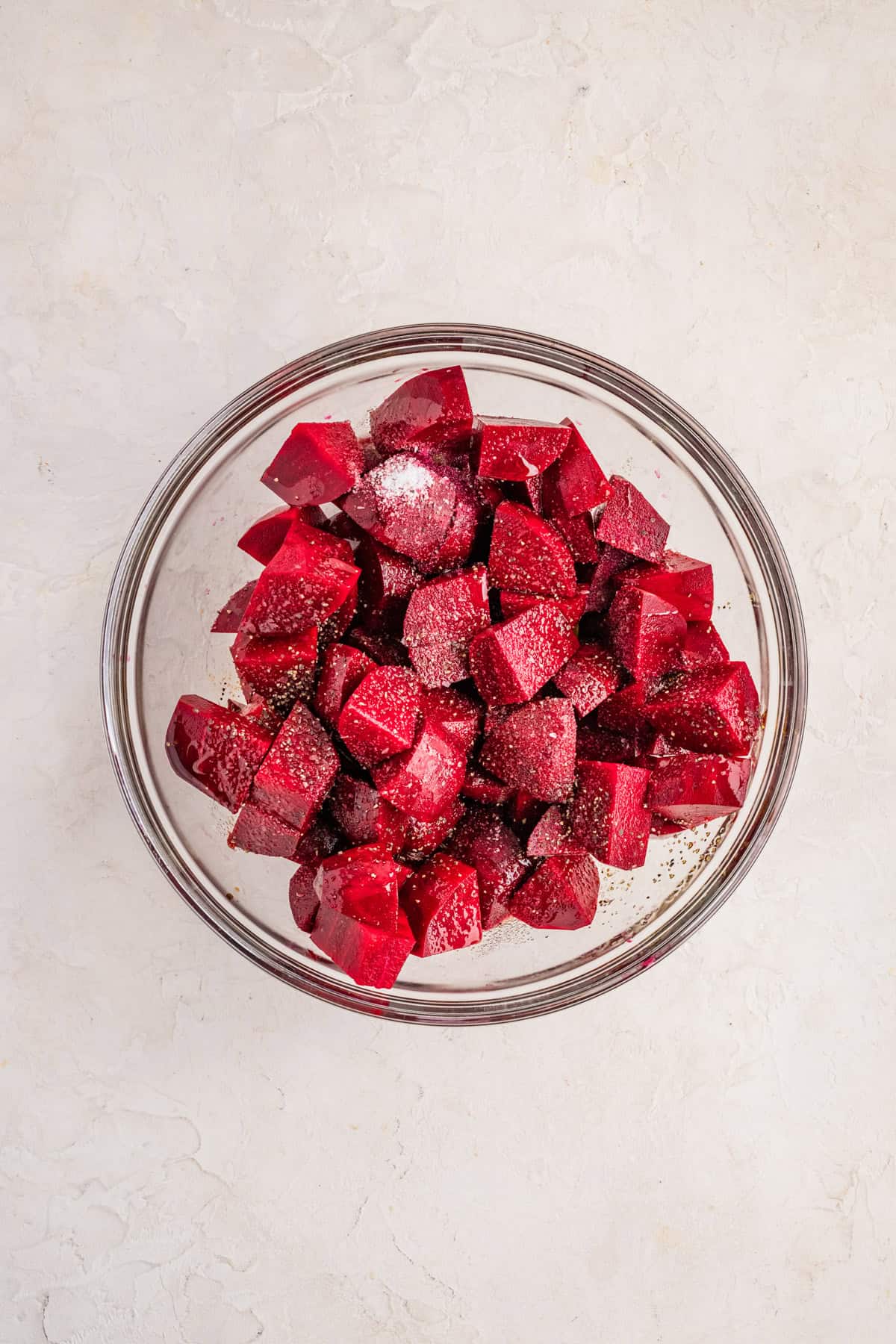 Raw beet cubes tossed in olive oil and balsamic vinegar in a large mixing bowl