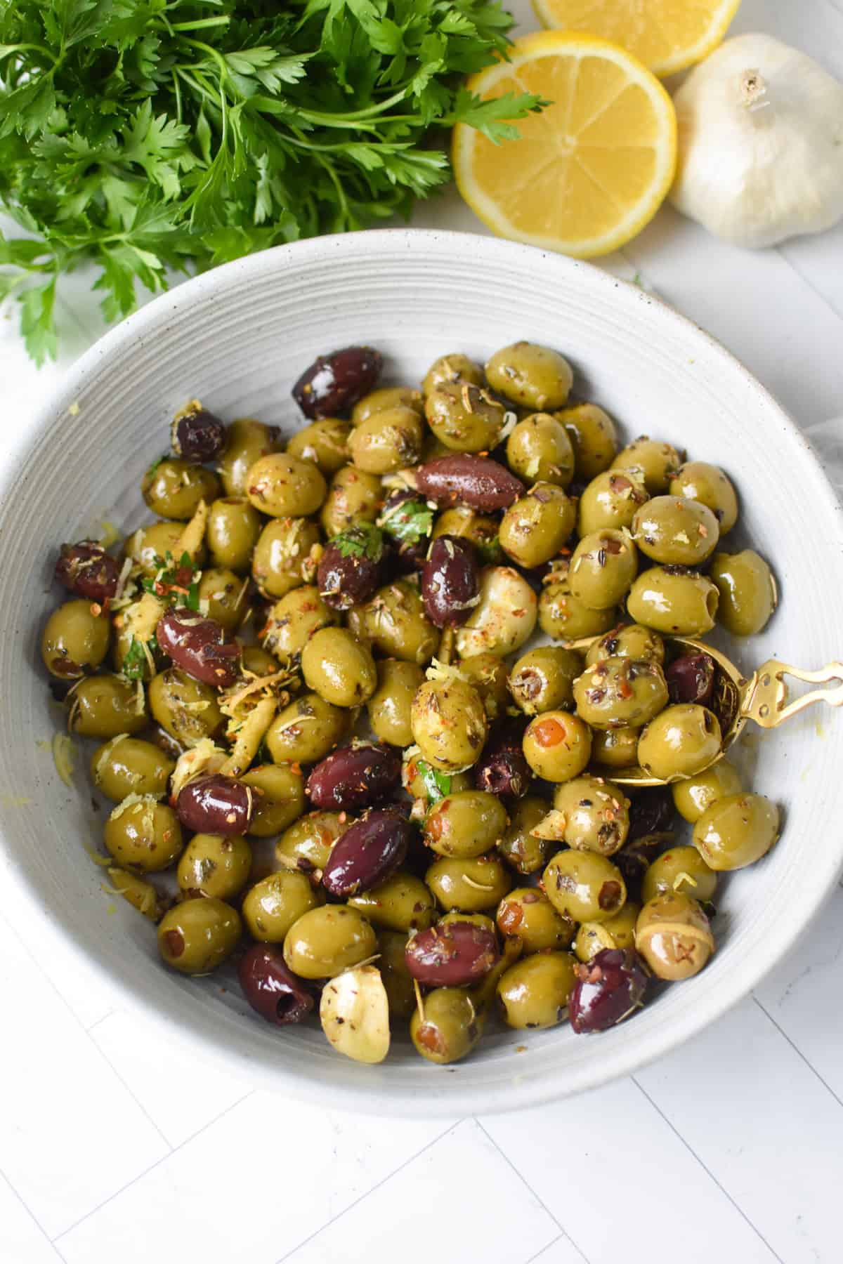 Warm olives with lemon and Mediterranean herbs in a white bowl