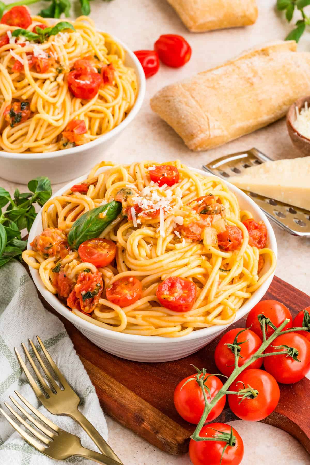 Close up of cherry tomato pasta with glossy tomato sauce and fresh basil leaves