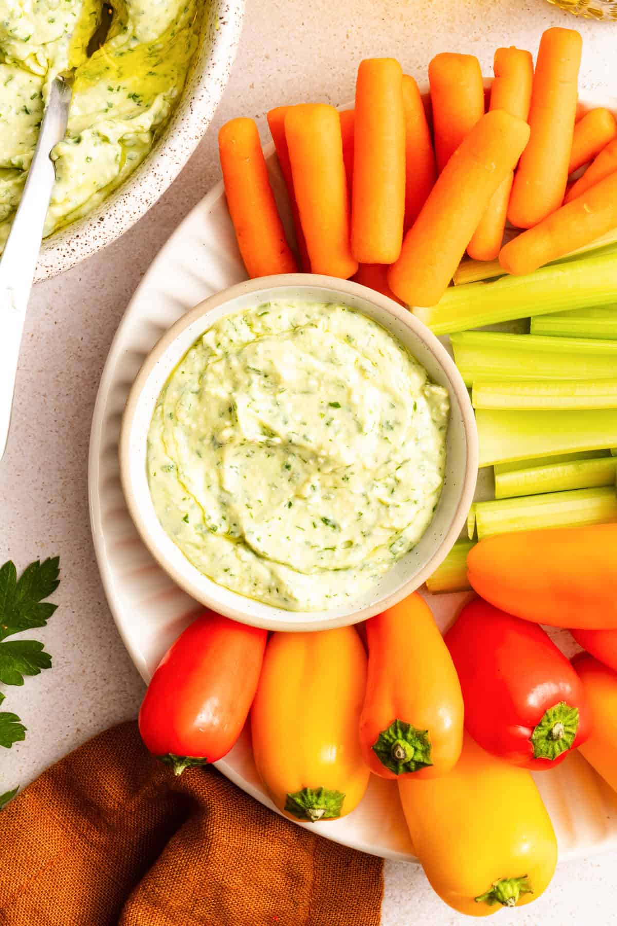 Green Goddess Dip with carrots, celery and bell peppers surrouding the dip