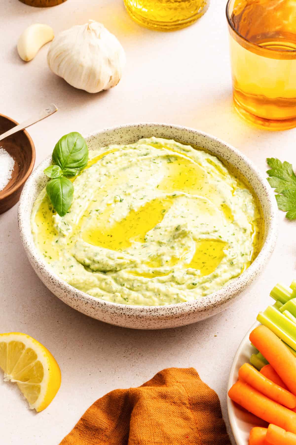 Green goddess dip with feta in a white bowl drizzled with olive oil