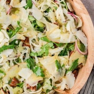 Apple fennel salad with pecans and shaved Parmesan in a tan bowl