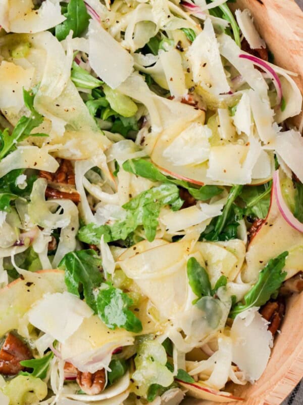 Apple fennel salad with pecans and shaved Parmesan in a tan bowl