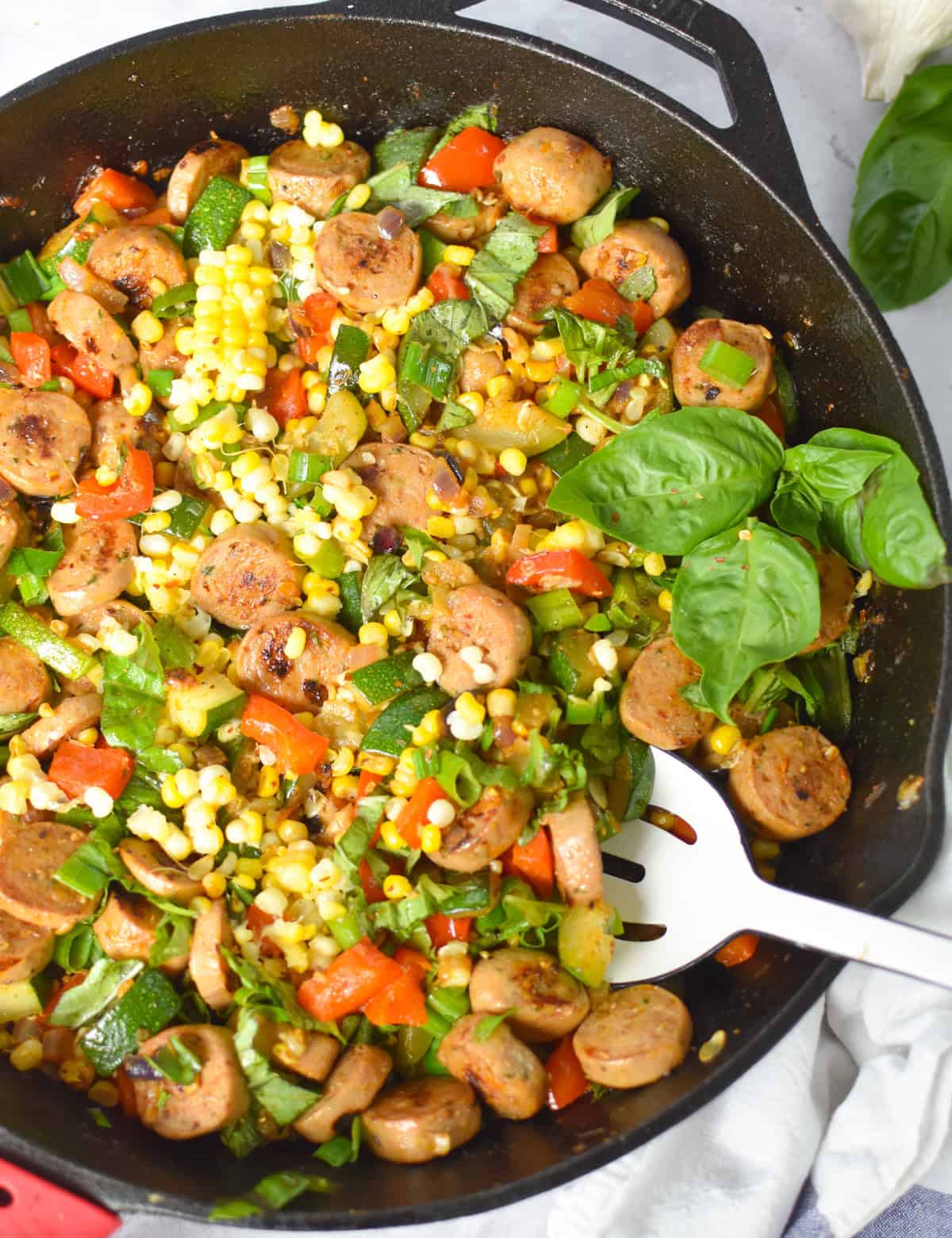 Cast iron skillet of sausage, zucchini, corn, and bell pepper ready to serve