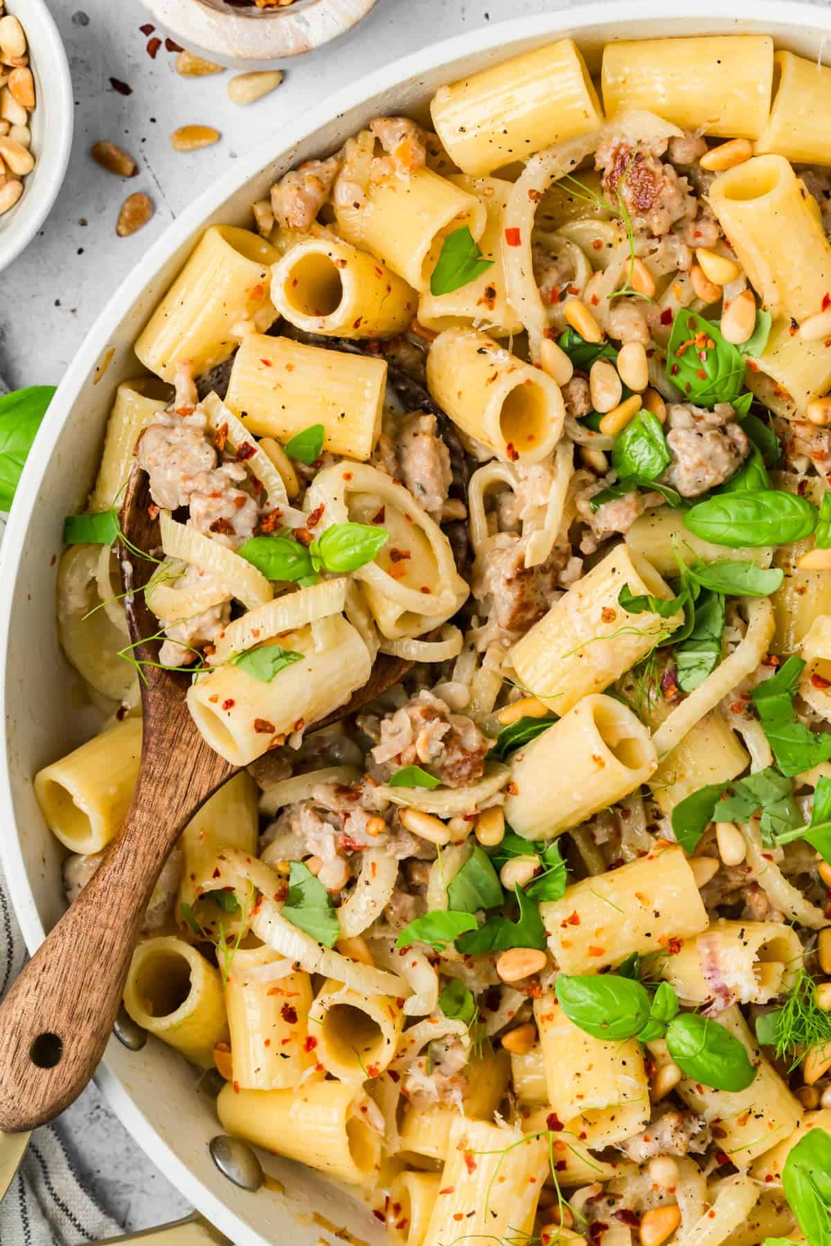 Close-up of creamy sausage and fennel pasta topped with toasted pine nuts and Parmesan