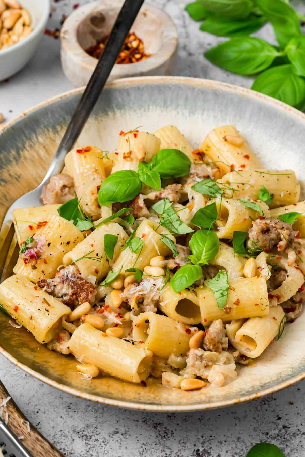 Creamy sausage and fennel pasta on a plate with a fork twirling rigatoni coated in white wine cream sauce