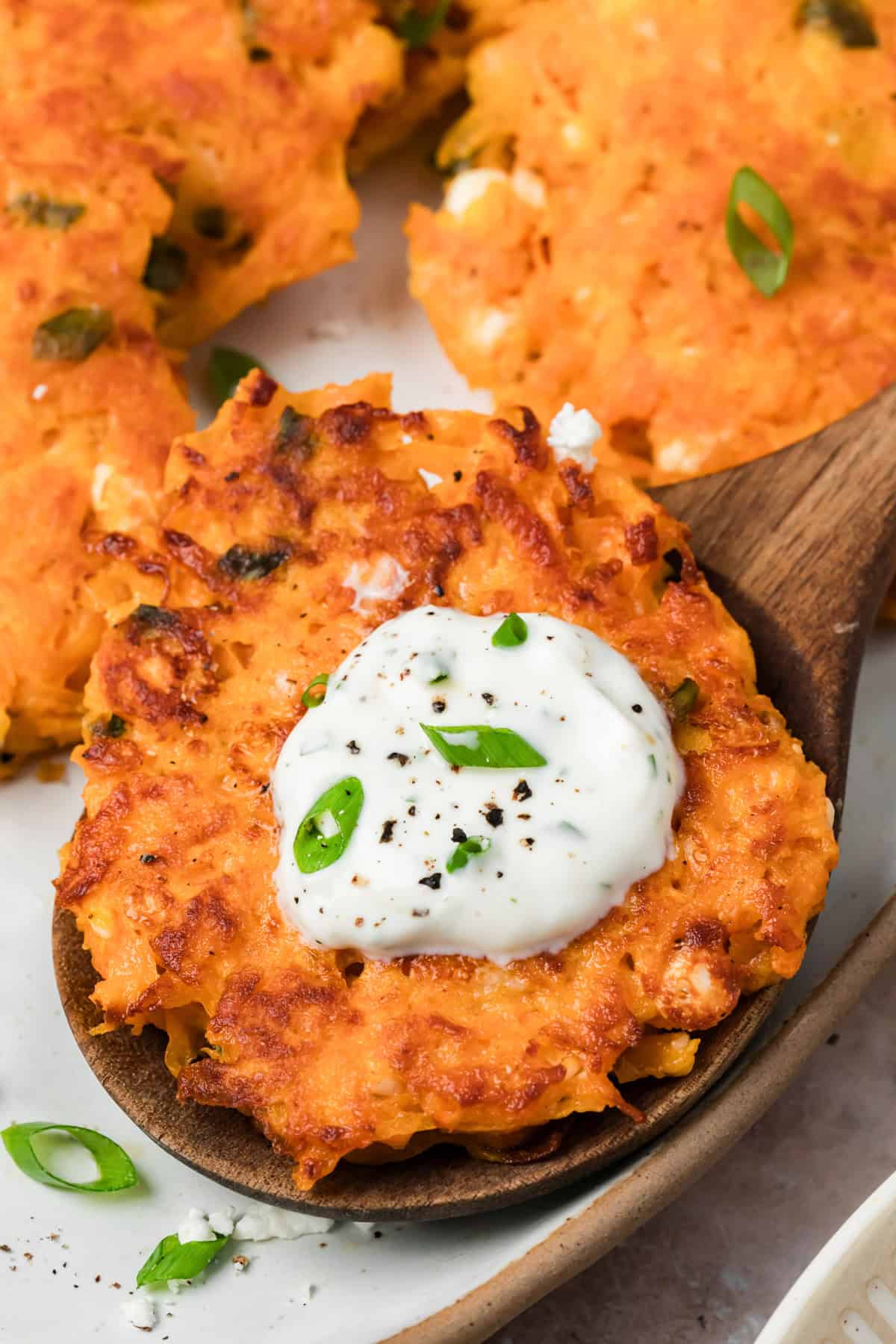 Sweet potato fritters with feta served on a spoon with lemon yogurt sauce