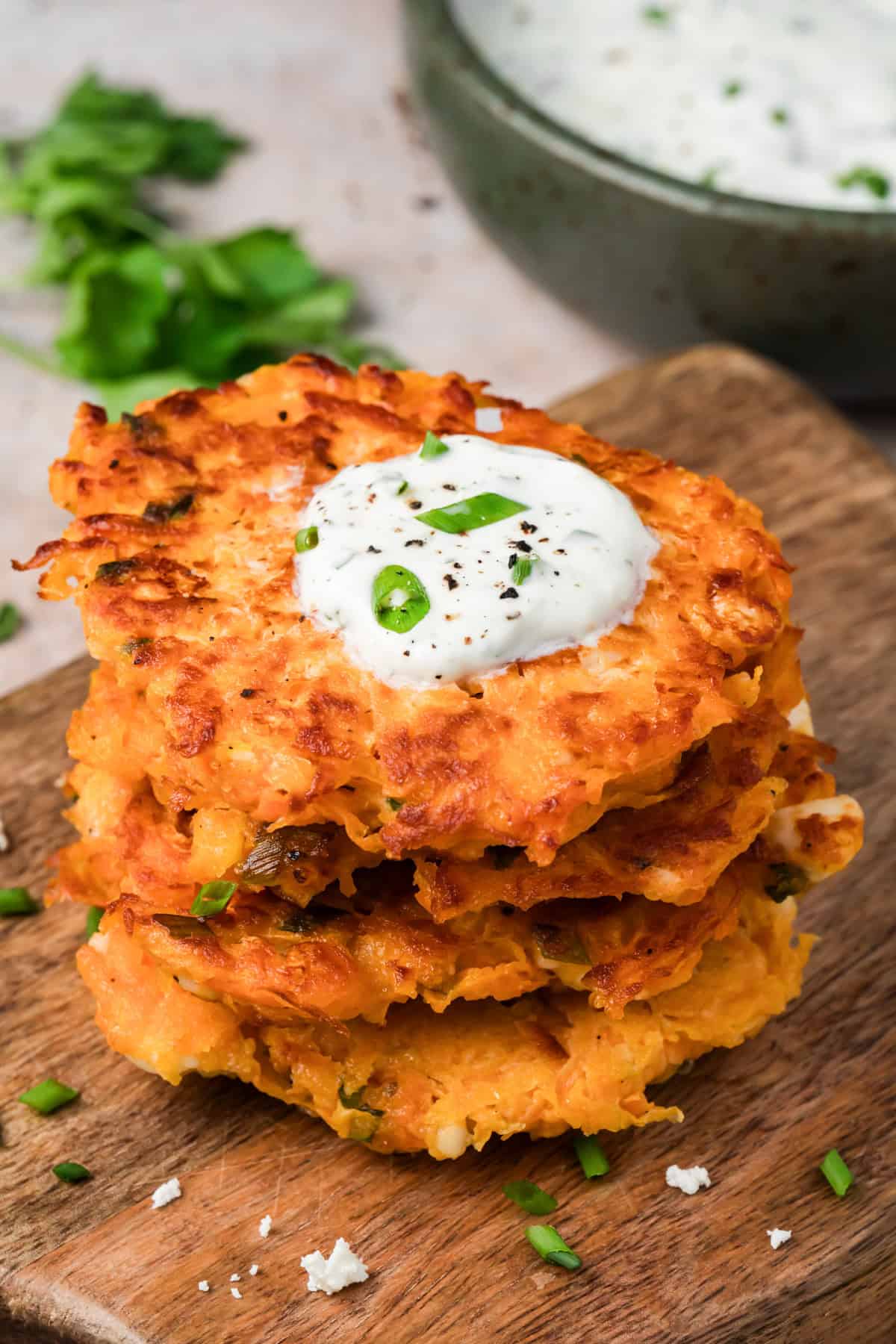Crispy sweet potato fritters with feta stacked on a plate with lemon herb yogurt sauce