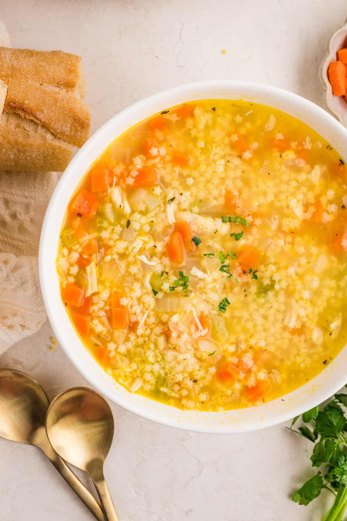 Bowl of chicken pastina soup with shredded chicken and tiny pasta in a clear broth, garnished with parsley